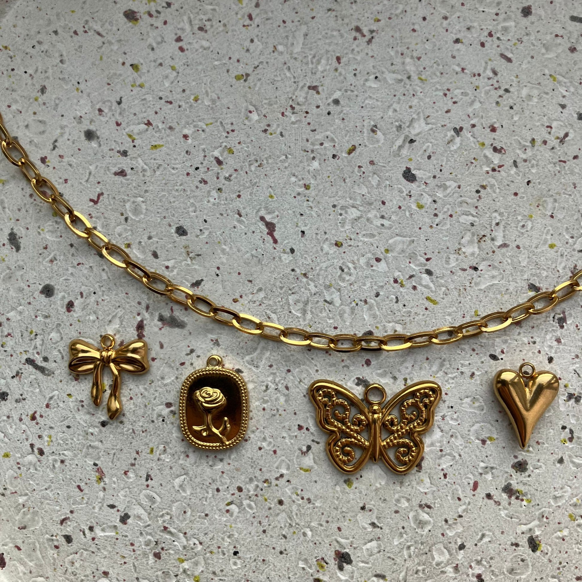 Gouden bedelketting met strikje, gouden plaat met roos, vlinder, hartje en zonnebloem | Zafia Jewellery