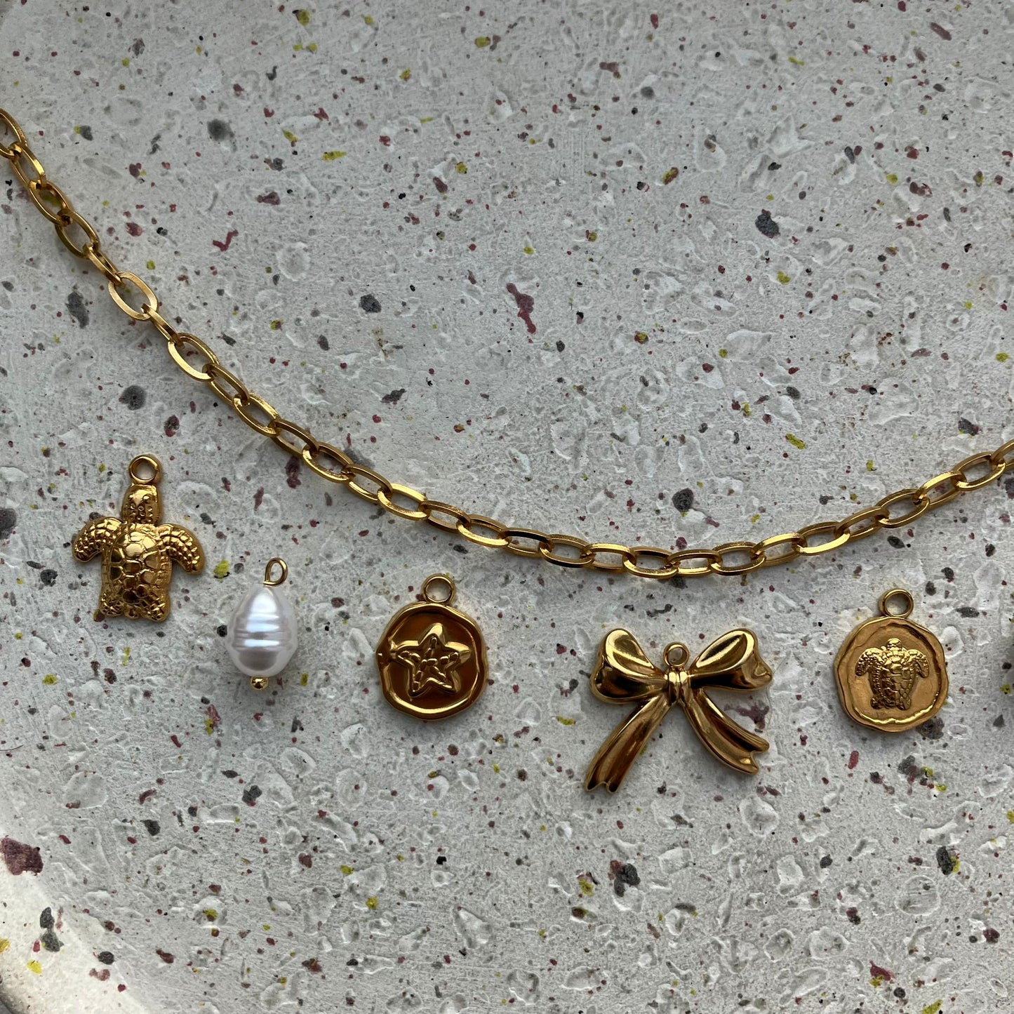 Close-up van vijf bedels: schildpad, parel, gouden zeesterbedel, sierlijk strikje en ronde bedel met schildpad | Zafia Jewellery