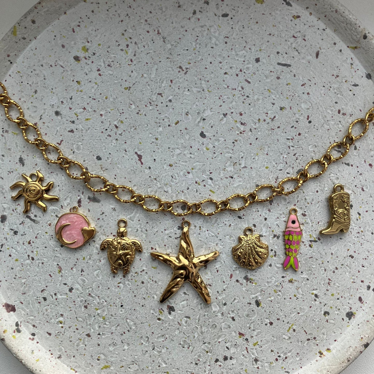 Gouden bedelketting met zeven bedels: zon, roze met goud, schildpad, zeester, schelp, visje met kleur, cowboylaars | Zafia Jewellery