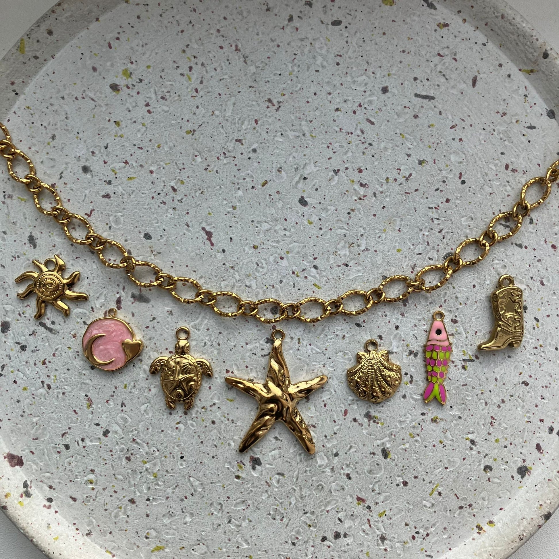 Gouden bedelketting met zeven bedels: zon, roze met goud, schildpad, zeester, schelp, visje met kleur, cowboylaars | Zafia Jewellery