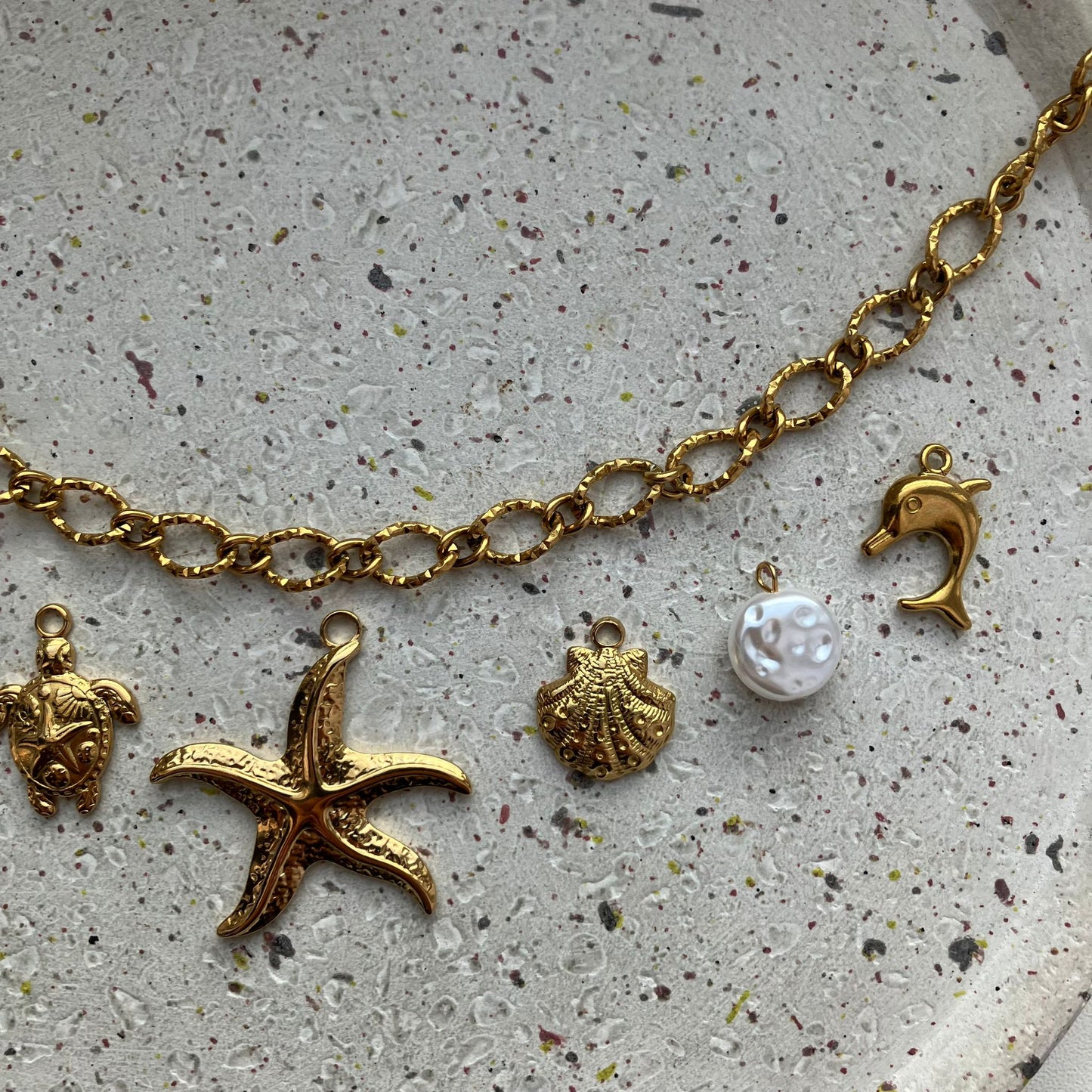 Gouden bedelketting met zeven bedels: zon, parel, schildpad, zeester, schelp, parel en dolfijn | Zafia Jewellery