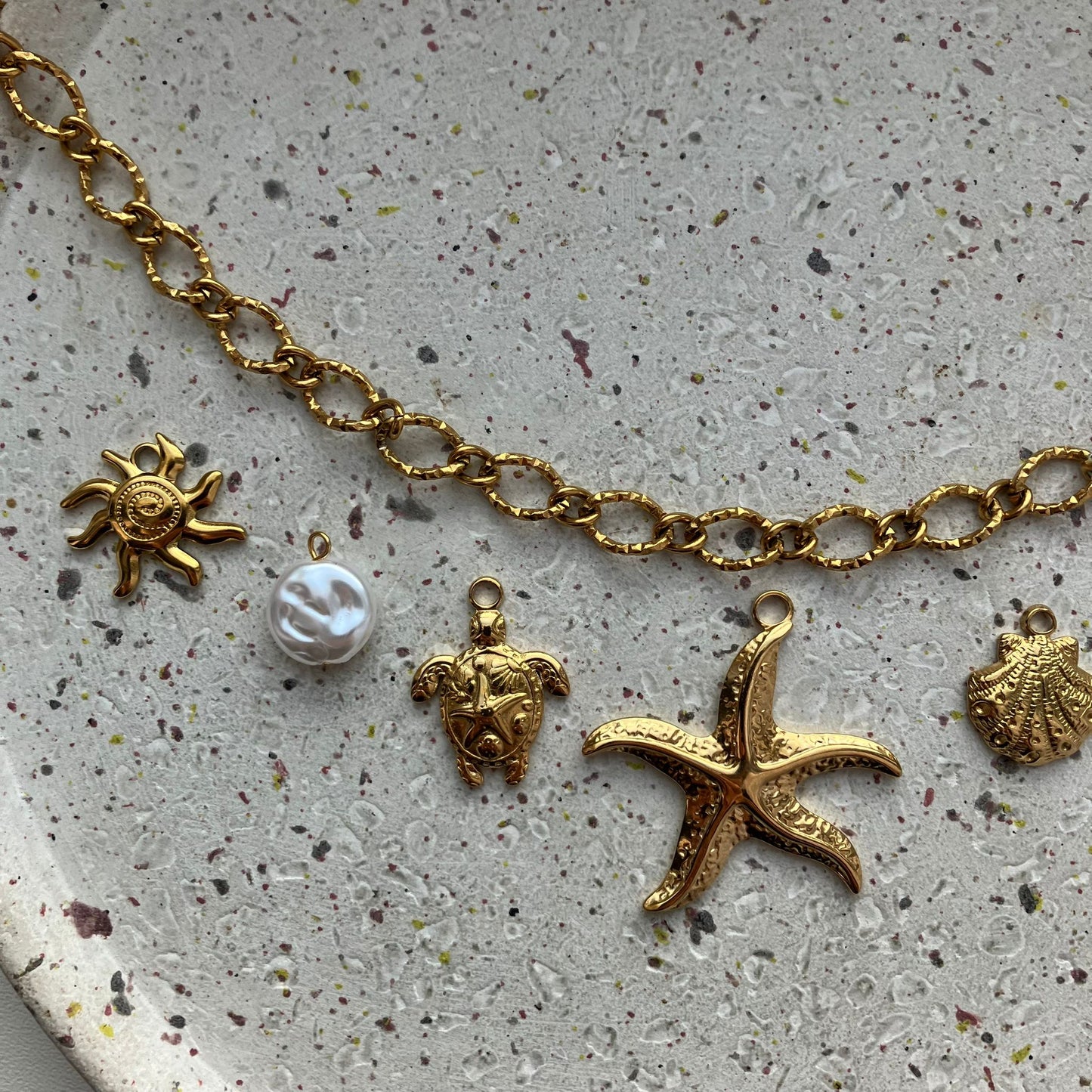 Gouden bedelketting met zeven bedels: zon, parel, schildpad, zeester, schelp, parel en dolfijn | Zafia Jewellery