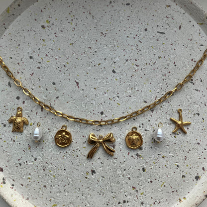 Gouden bedelketting met schakel en 7 bedels: schildpad, parel, ster, strik, schildpad, parel en zeester | Zafia Jewellery