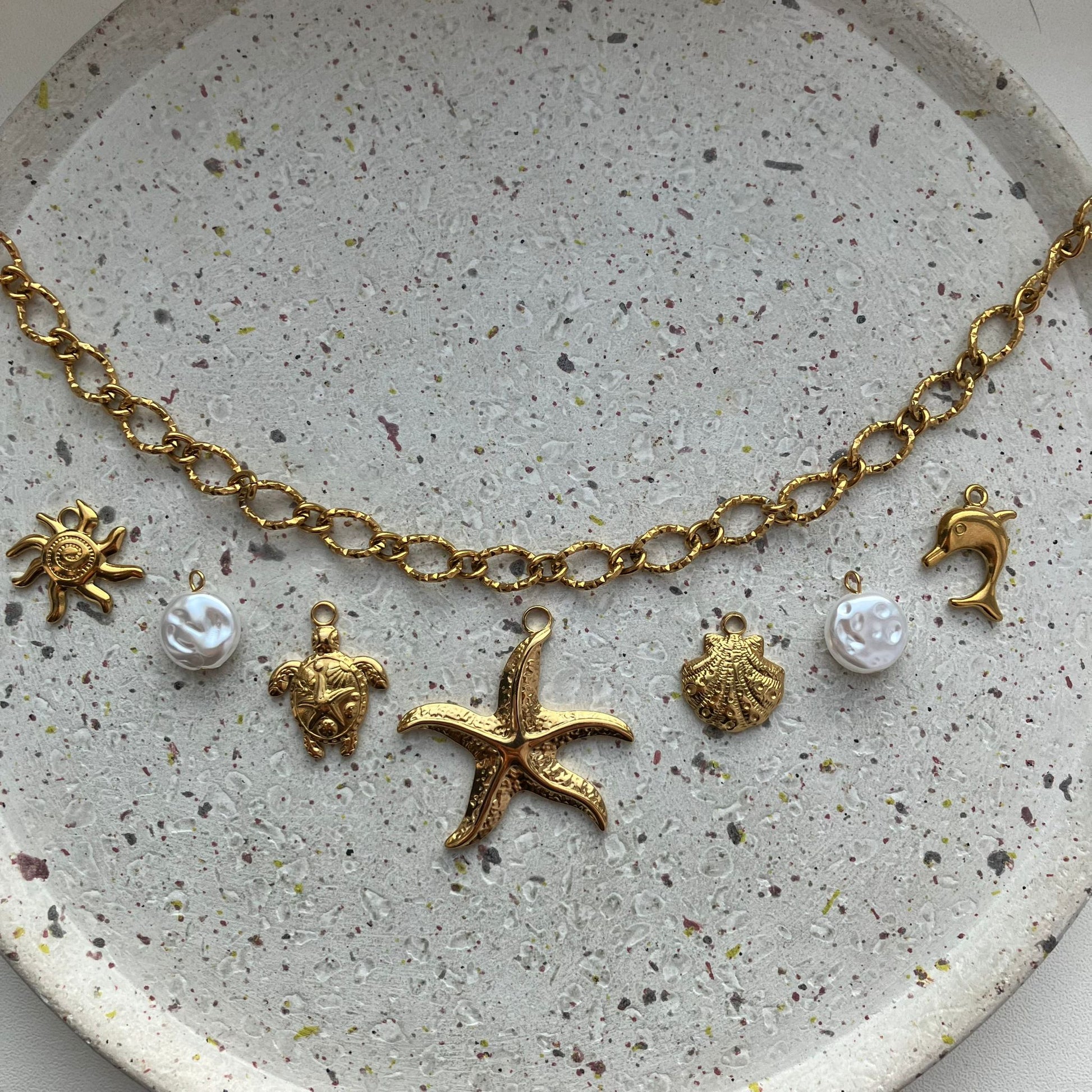 Gouden bedelketting met zeven bedels: zon, parel, schildpad, zeester, schelp, parel en dolfijn | Zafia Jewellery