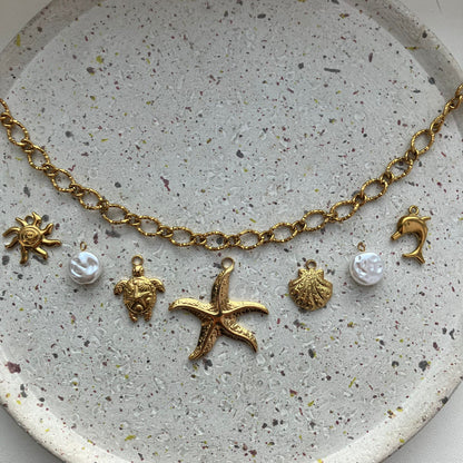 Gouden bedelketting met zeven bedels: zon, parel, schildpad, zeester, schelp, parel en dolfijn | Zafia Jewellery