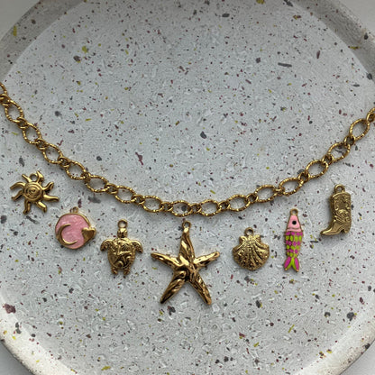 Gouden bedelketting met zeven bedels: zon, roze met goud, schildpad, zeester, schelp, visje met kleur, cowboylaars | Zafia Jewellery